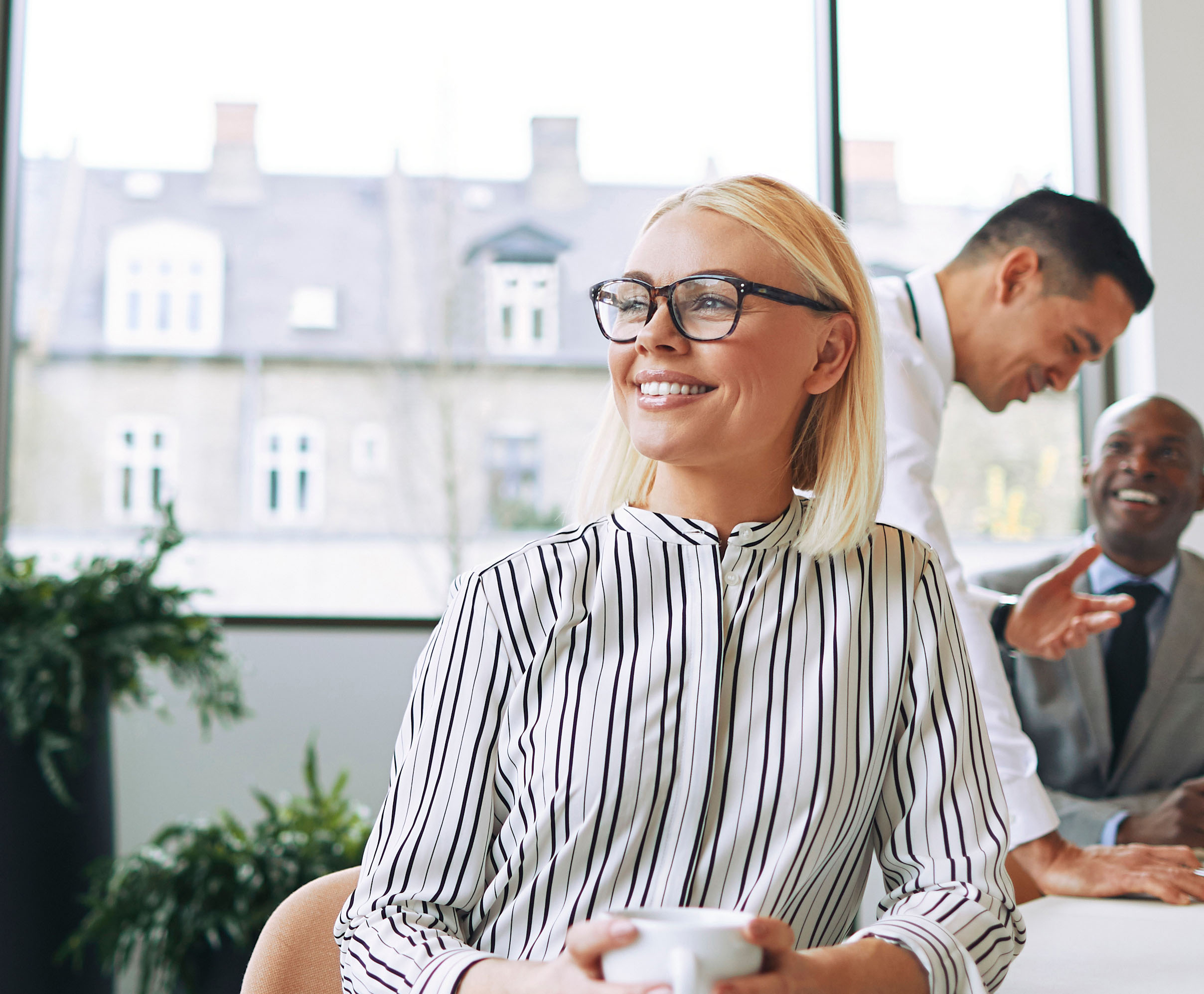 Smiling Young Businesswoman Enjoying Her Coffee During An Office Break